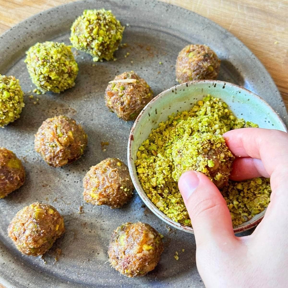 Hand rolling date balls in ground pistachio.