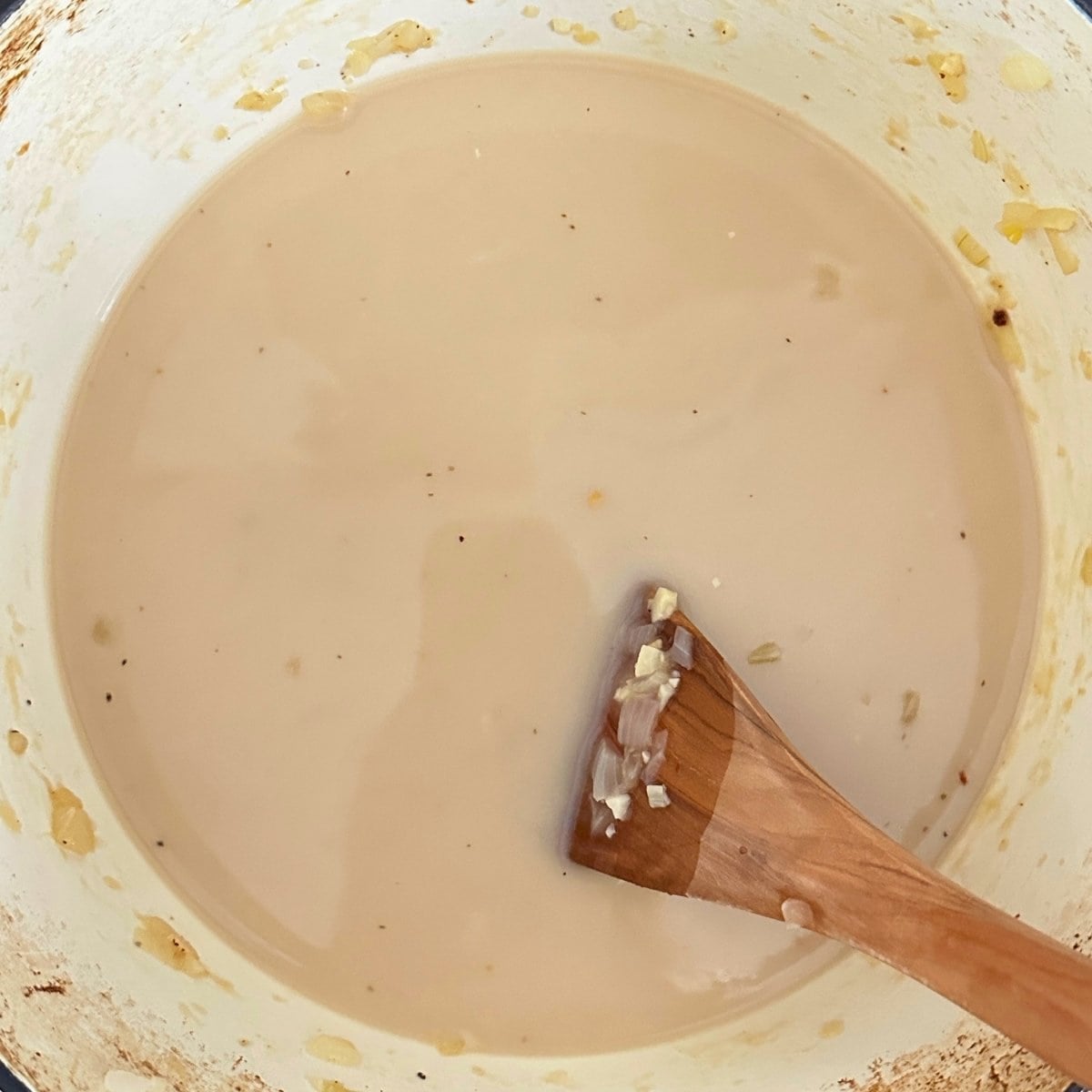 Coconut milk, broth, lime juice, white wine vinegar, and maple syrup added to the cooked onions.
