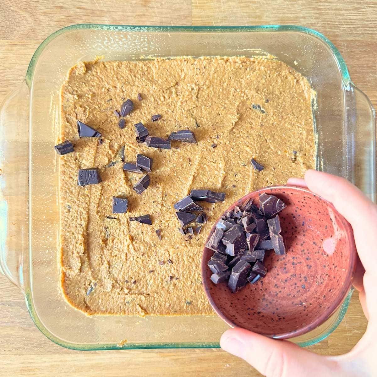 Sprinkling chopped dark chocolate over the unbaked pumpkin blondie.