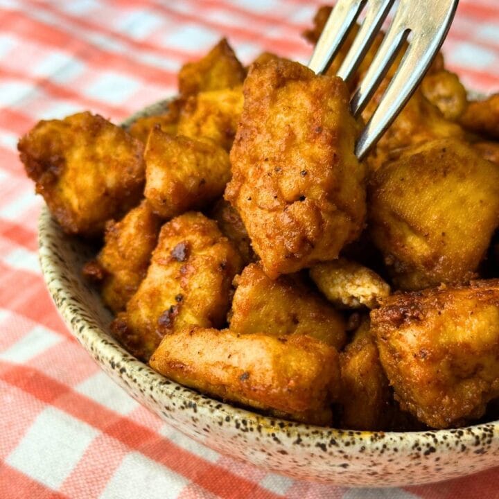 Baked BBQ tofu nuggets in a bowl with a fork in one.