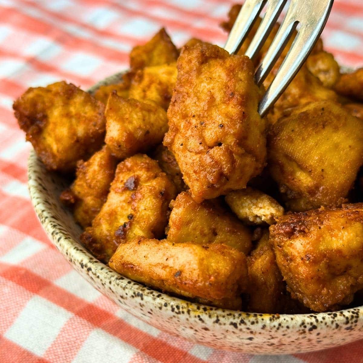 Baked BBQ Tofu nuggets in a bowl with a fork poked into one.