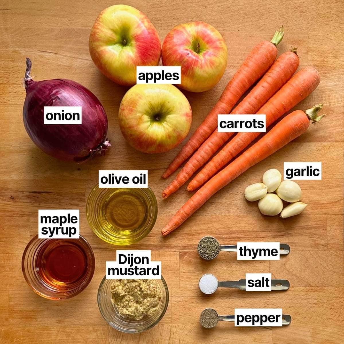Ingredients to make maple dijon carrots with corresponding labels: onion, apples, carrots, garlic, olive oil, maple syrup, Dijon mustard, thyme, sea salt, and pepper.
