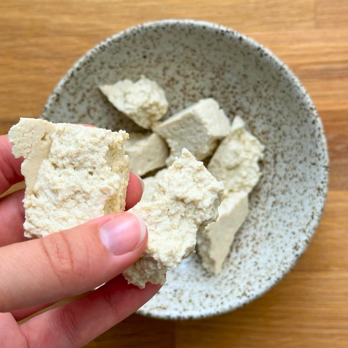 Using hands to rip tofu into nuggets.