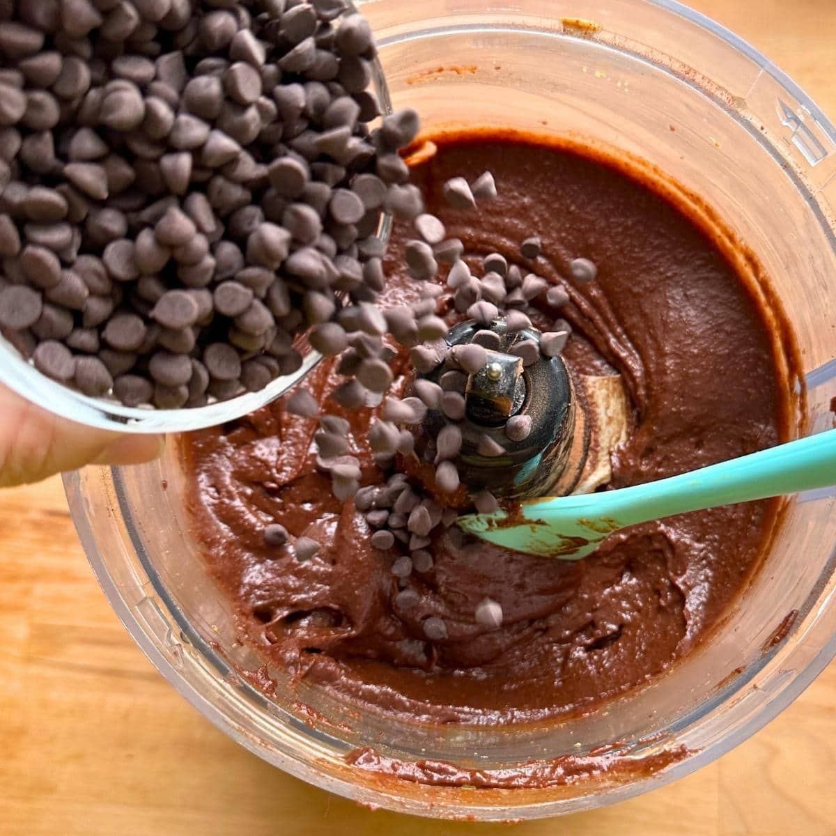 Sprinkling chocolate chips into chickpea brownie batter.