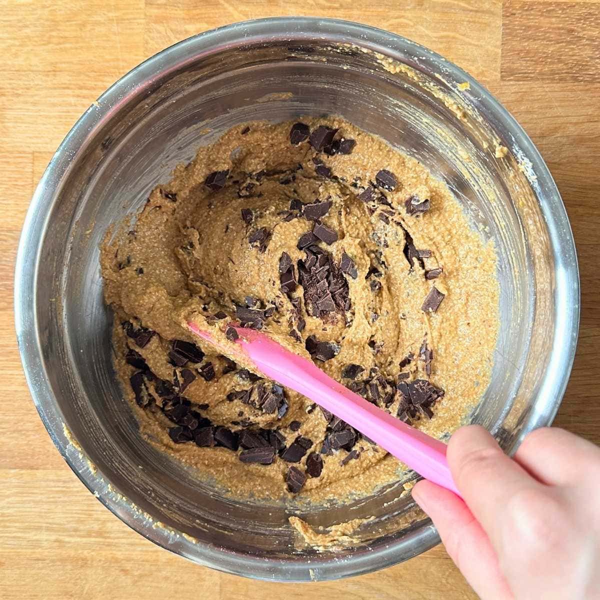 Mixing wet ingredients and chocolate chip into the dry to make pumpkin cookie dough.