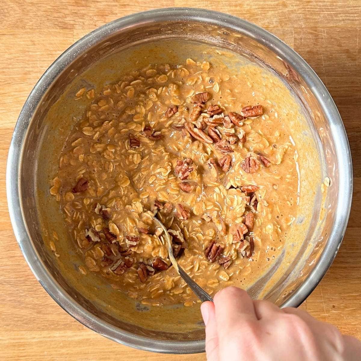 Mixing pecans into the pumpkin oatmeal mixture.