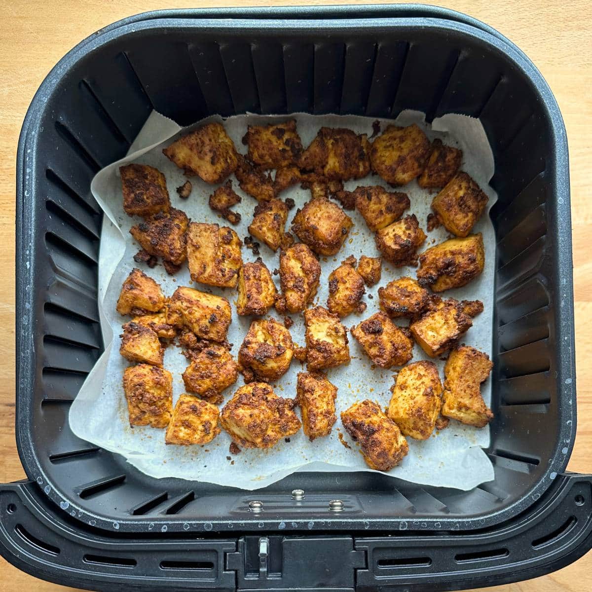Seasoned tofu bites crispy in air fryer after cooking.