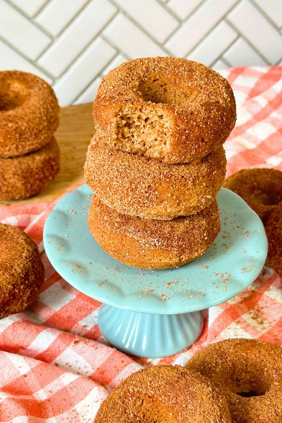 Stack of three vegan baked apple cider donuts with a bite taken out of the top one.