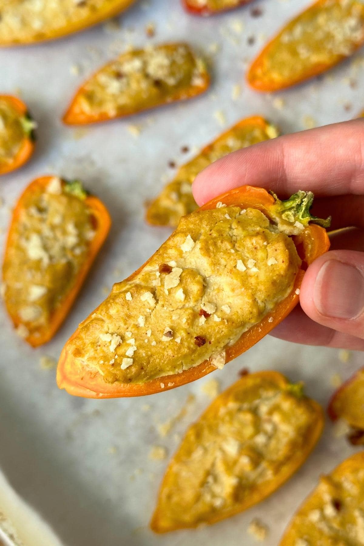 Mini pepper popper with vegan cheesy tofu filling and crushed tortilla chips on top.