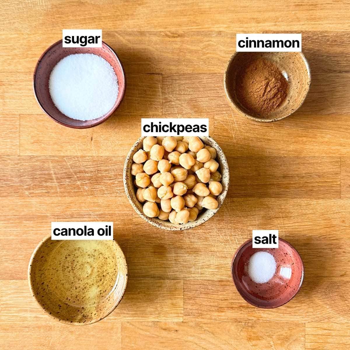 Ingredients needed to make cinnamon sugar chickpeas with labels: sugar, cinnamon, chickpeas, canola oil, and salt.