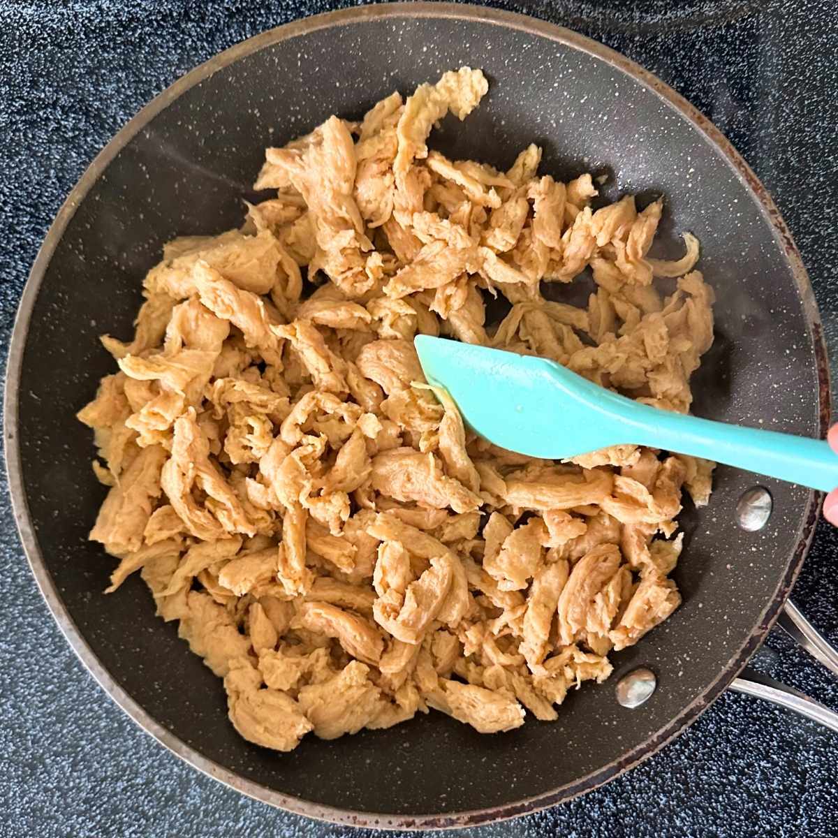Cooking rehydrated soy curls shreds in a pan on the stove.