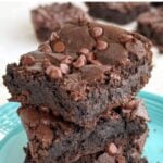 Stack of 3 flourless chickpea brownies on a blue plate.