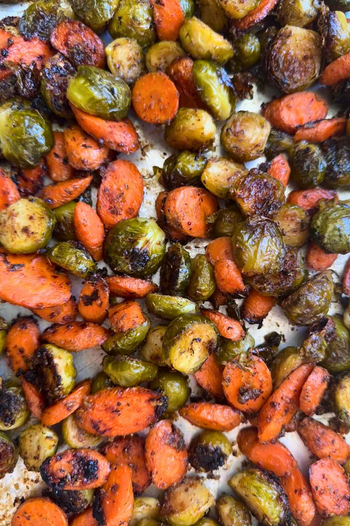 Crispy maple Dijon glazed carrots and Brussels sprouts on a baking sheet.