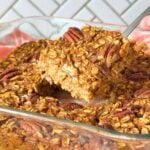 Square of vegan pumpkin baked oatmeal being lifted out of a pan of more baked oatmeal squares.