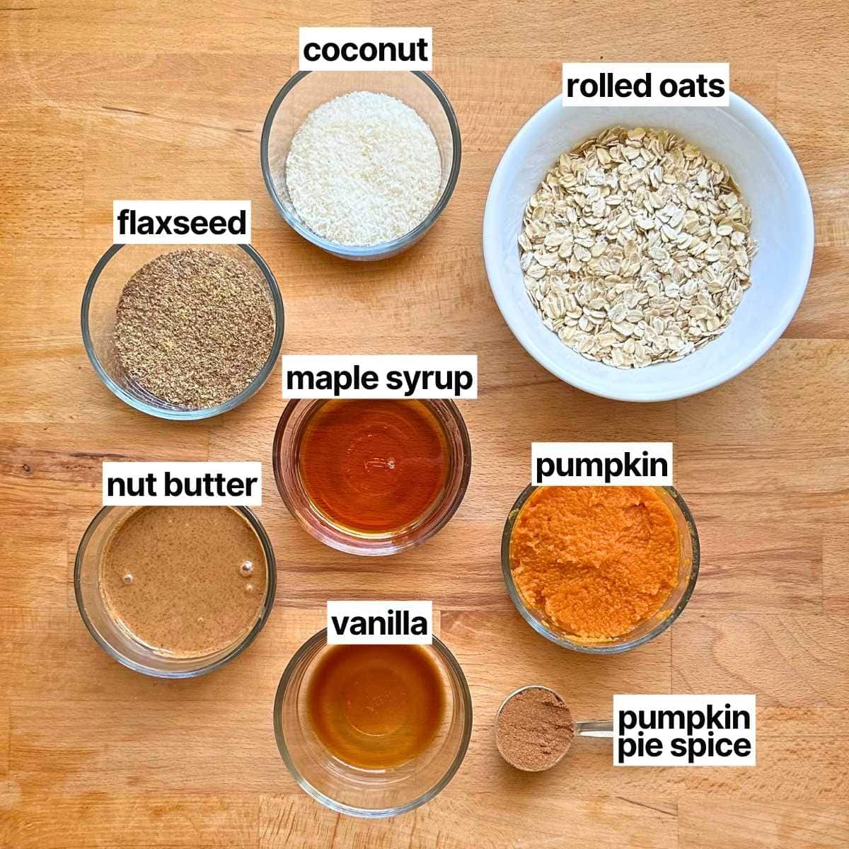 Ingredients needed to make pumpkin protein balls with labels: coconut, rolled oats, flaxseed, maple syrup, nut butter, vanilla, pumpkin, pumpkin pie spice.