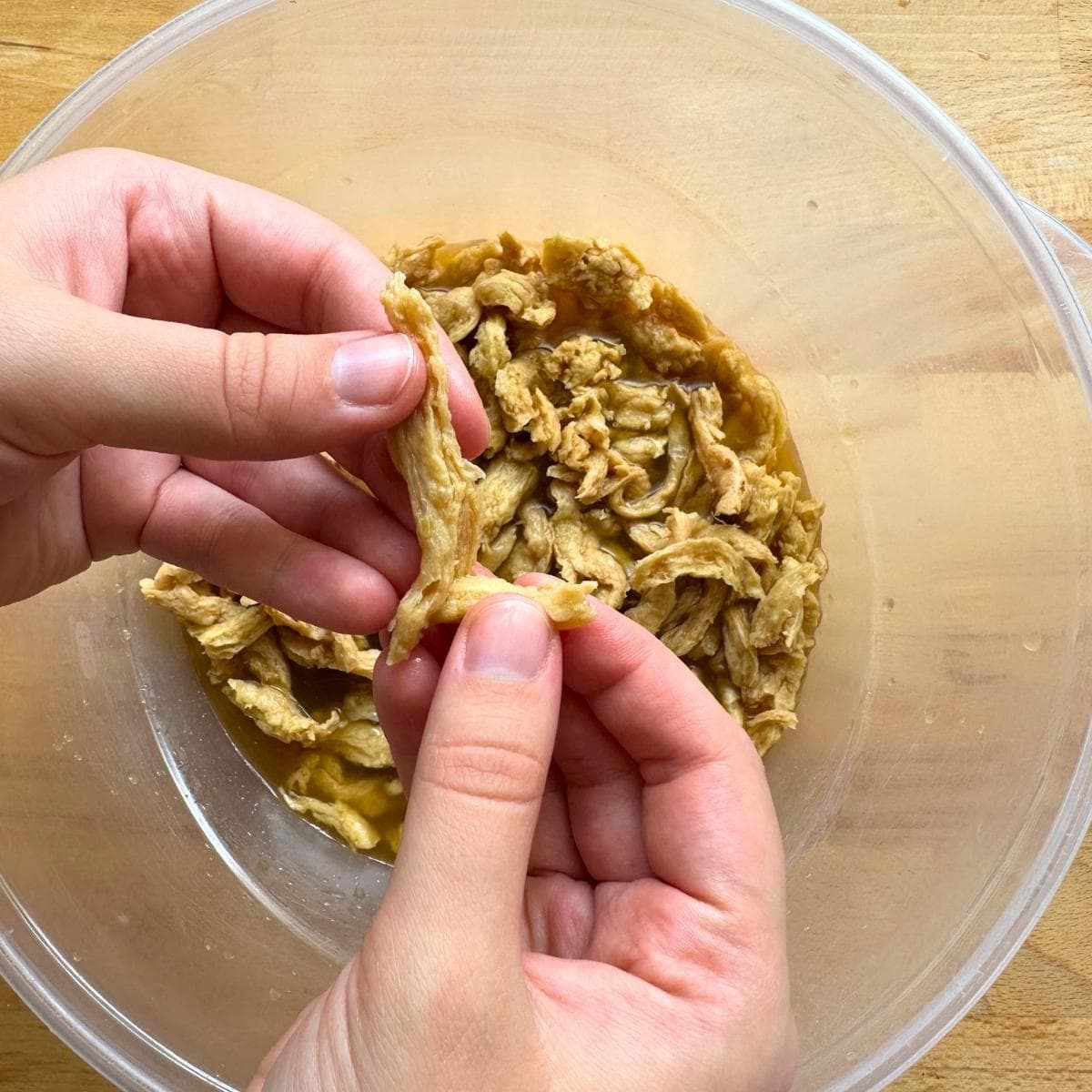 Shredding rehydrated soy curls by hand into small pieces.