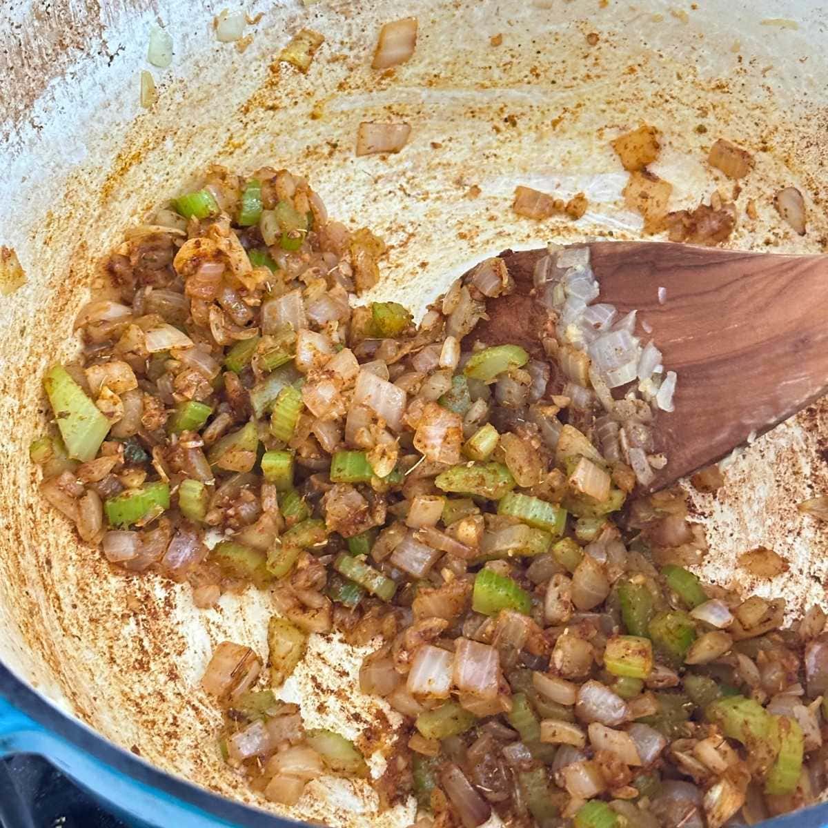 Cooking onion, celery, and spices in a soup pot.