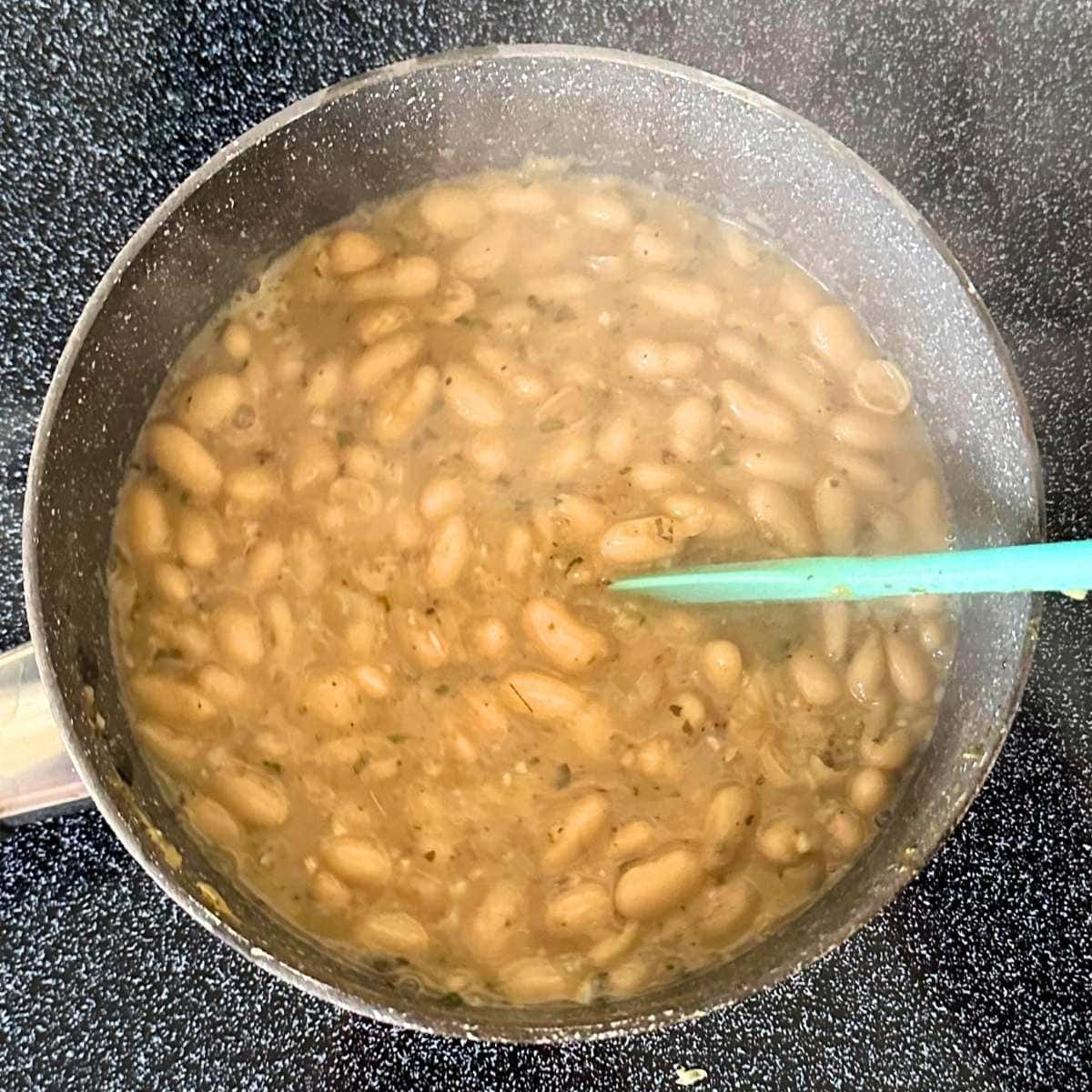 Smash down beans as they cook with a spatula.