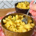 Bowl of creamy vegan butternut squash mac and cheese with sliced basil leaf on top.