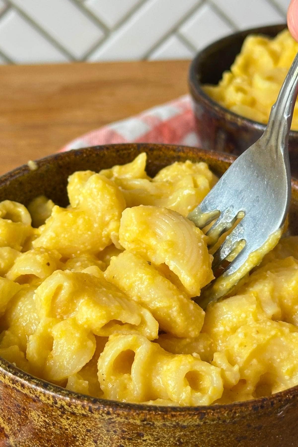Bowl filled with vegan butternut squash mac and cheese with a fork digging in.