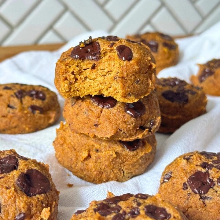 Stack of three vegan gluten-free pumpkin cookies with a bite taken out of the top one.