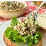 Vegan chicken salad with soy curls being spooned onto a piece of bread with lettuce.