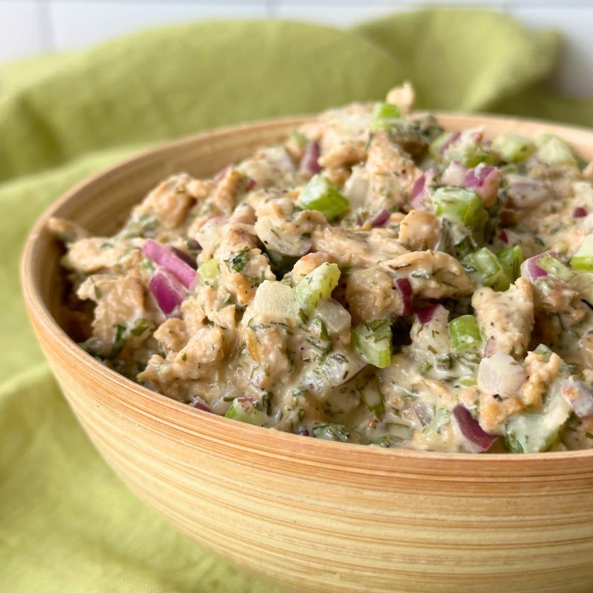Bowl of vegan chicken salad with soy curls mixed in a bowl with bits of red onion and celery.
