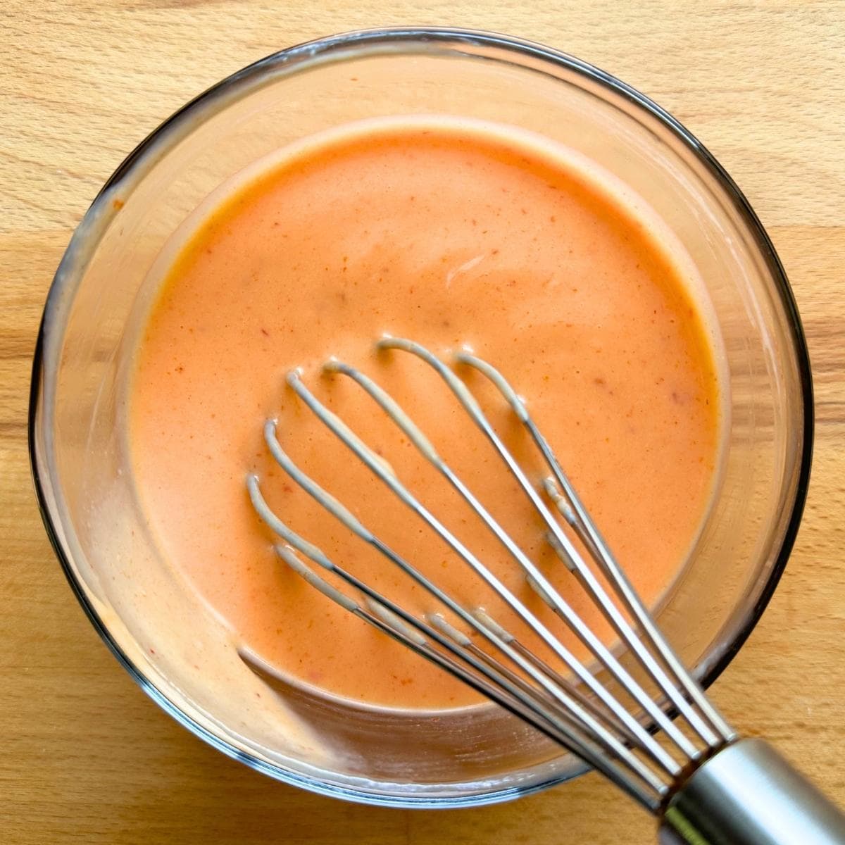 Whisking bang bang sauce in a small bowl.