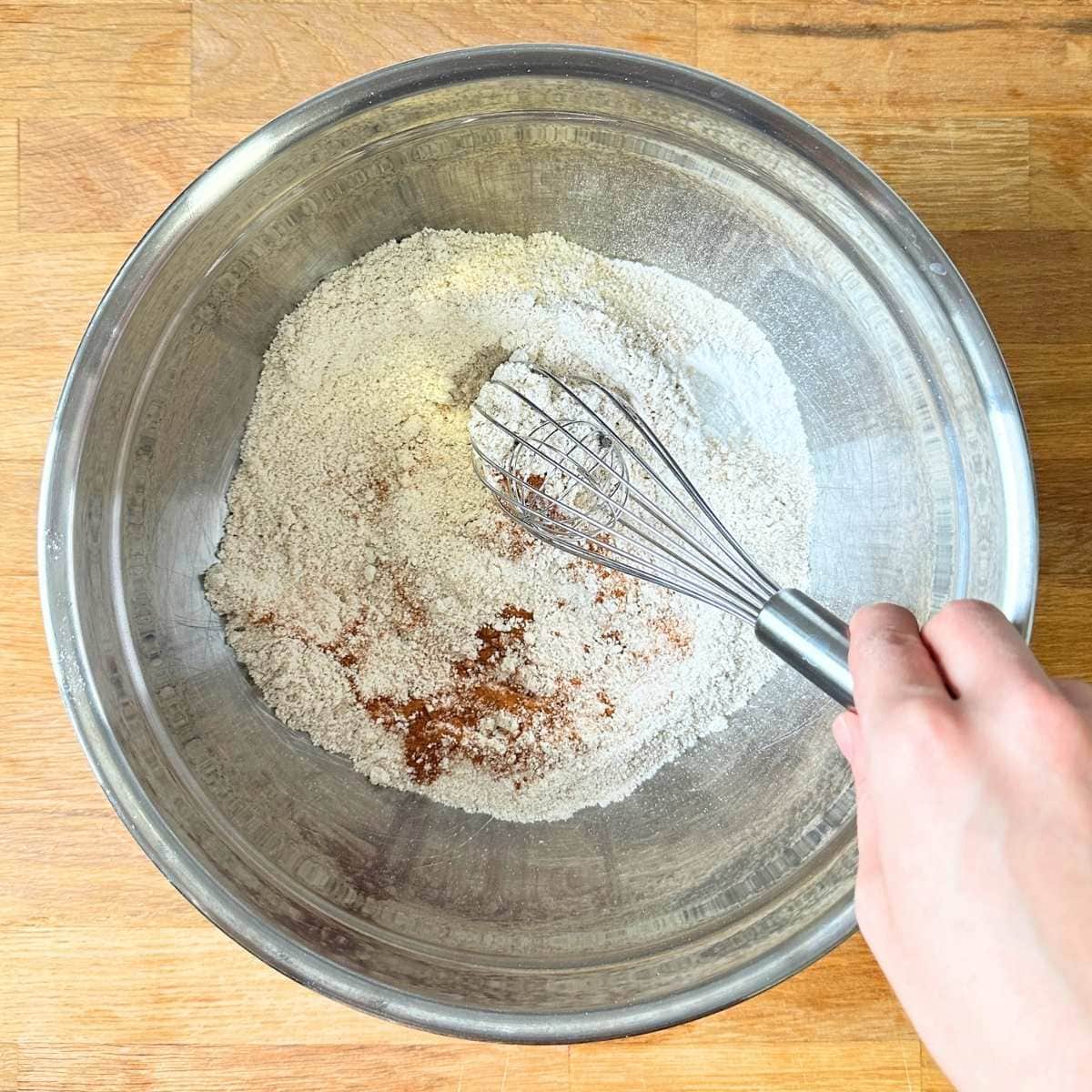 Whisking dry ingredients in a metal bowl.