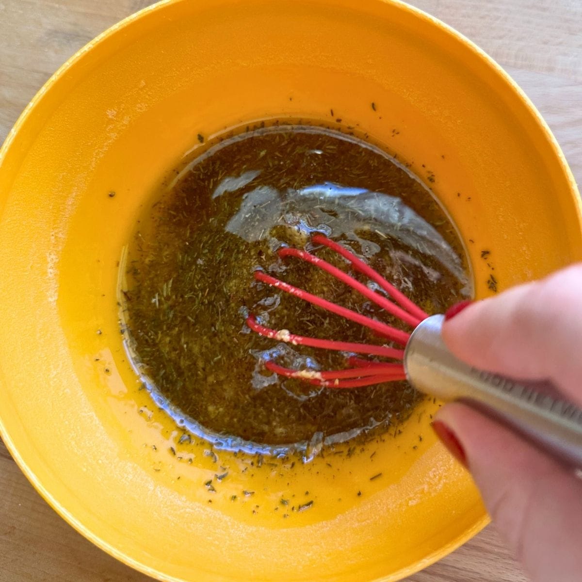 Whisking maple syrup and Dijon mustard with spices and oil in a small bowl to form glaze for veggies.