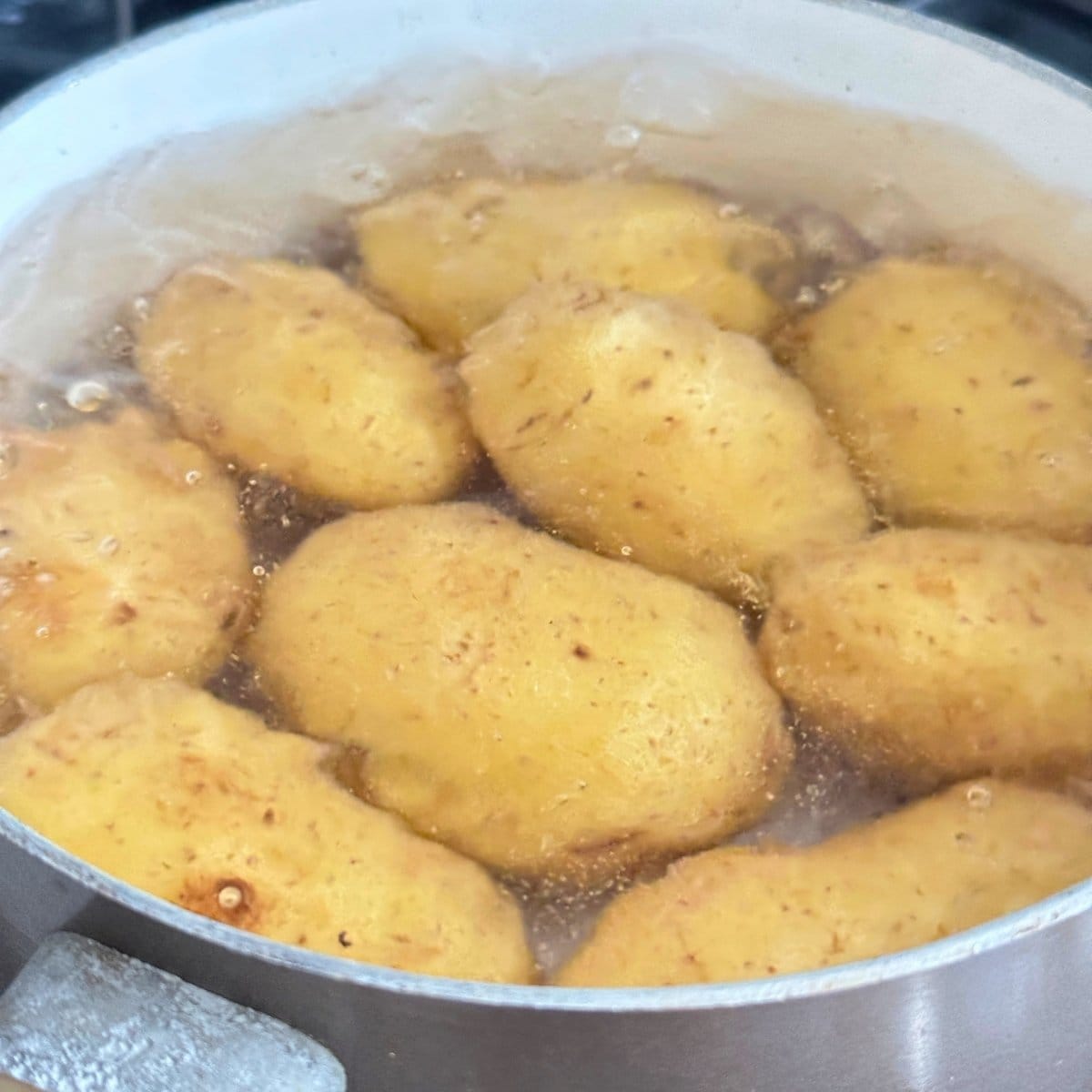 Baby potatoes boiling in a pot of water.
