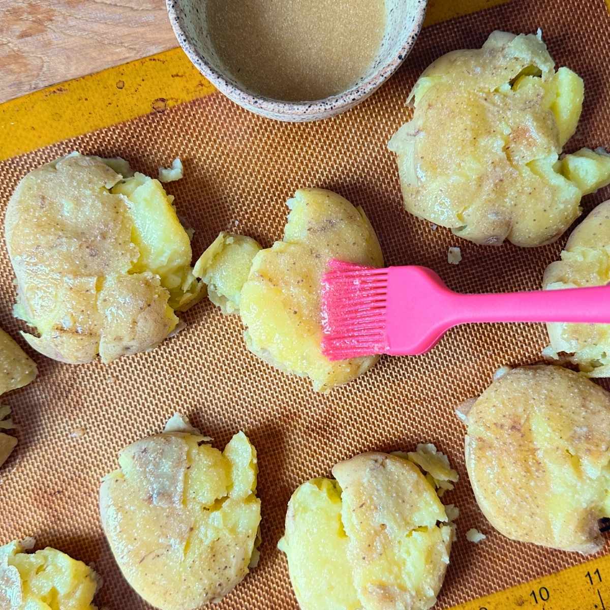 Brushing smashed potatoes with garlic aquafaba mixture.