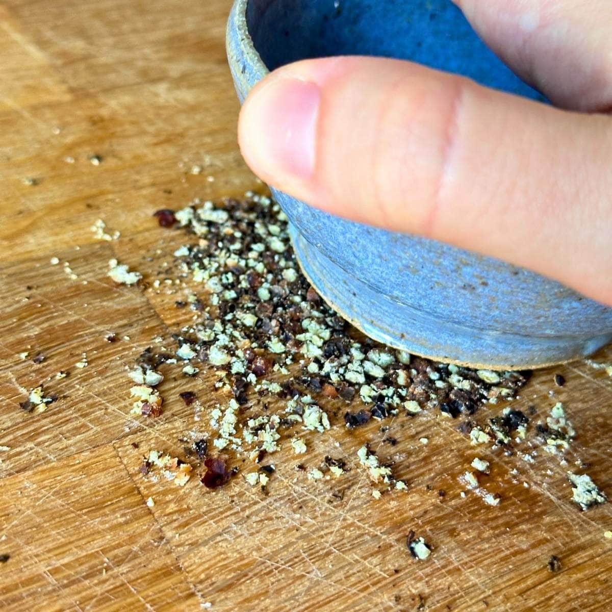 Crushing pepper with the bottom of a bowl.