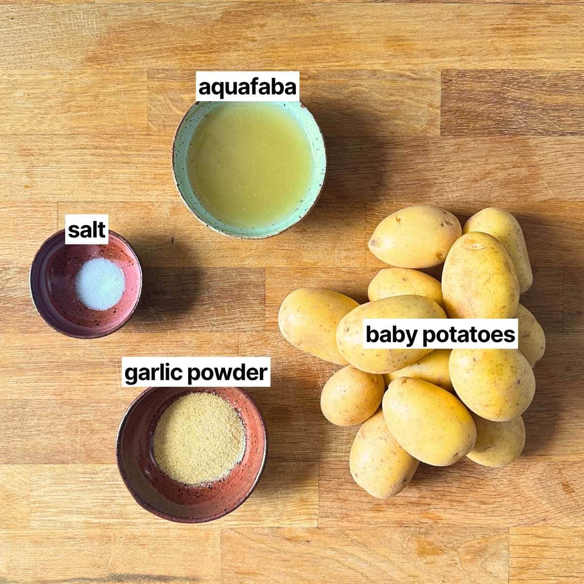 Ingredients needed to make garlic smashed potatoes without oil with labels: aquafaba, salt, garlic powder, and baby potatoes.