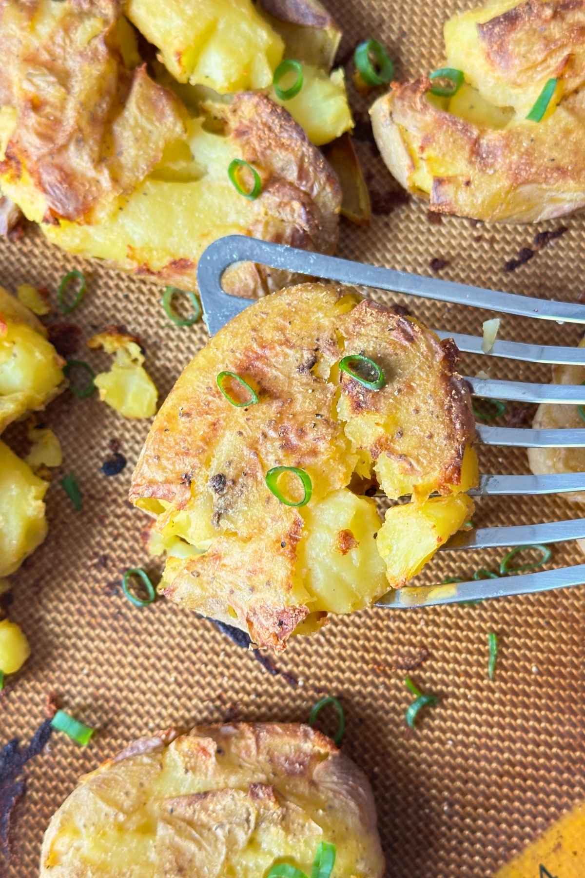 Crispy garlic smashed potato with green onion on top.