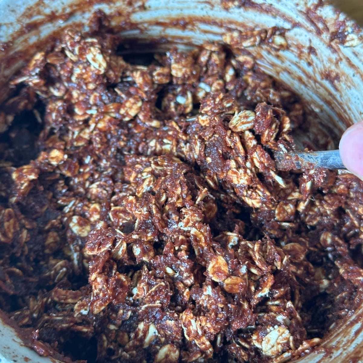 Mixing date and almond butter paste with cocoa powder and oats to form the no bake cookie dough.