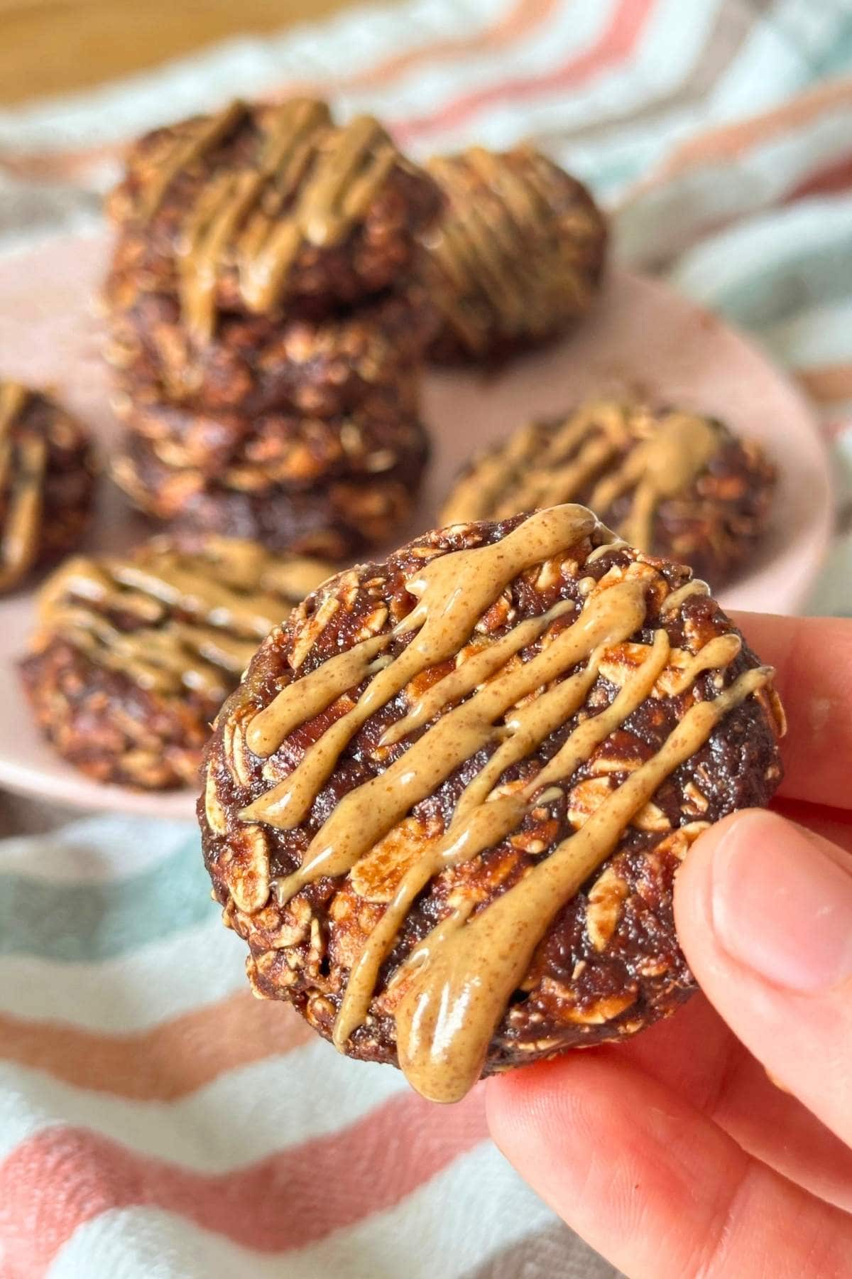 No-bake date cookie with almond butter drizzled on top, more cookies are in the background.