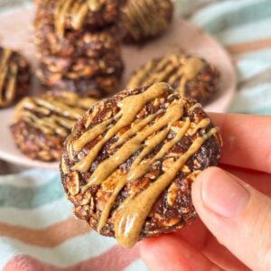 No-bake date cookie with almond butter drizzled on top, more cookies are in the background.