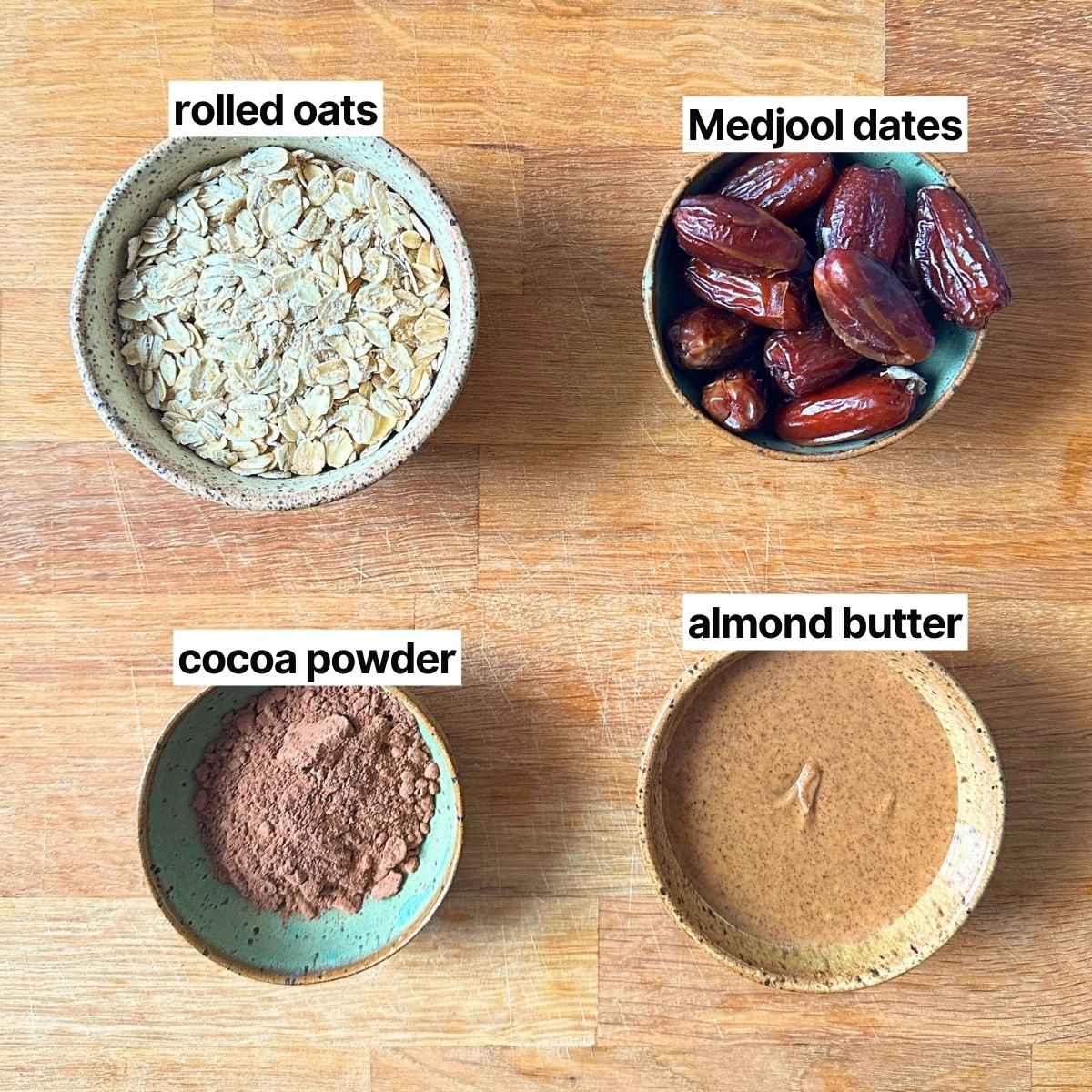 Ingredients needed to make no-bake date cookies with labels: rolled oats, Medjool dates, cocoa powder, and almond butter.