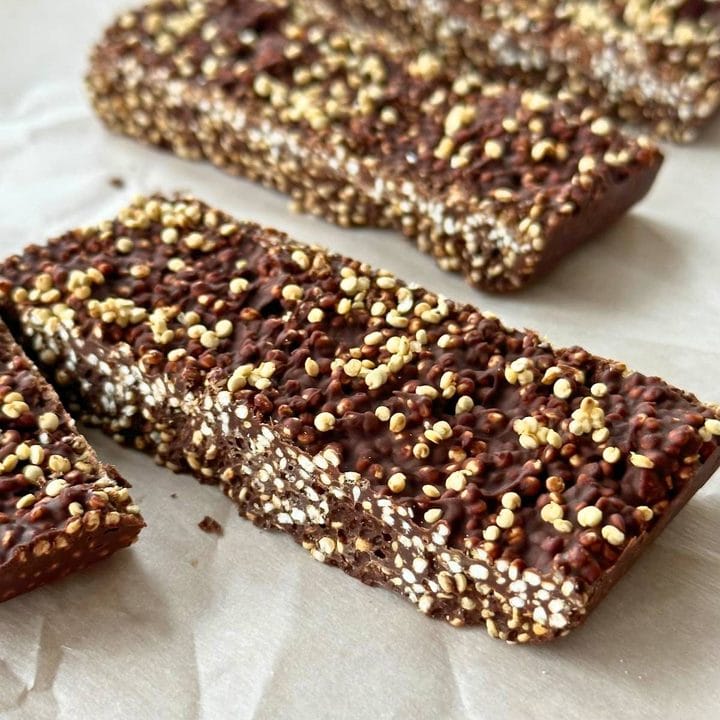 Chocolate quinoa crunch bars on sheet of parchment paper, the bars are sliced through so you can see the quinoa cut in half.