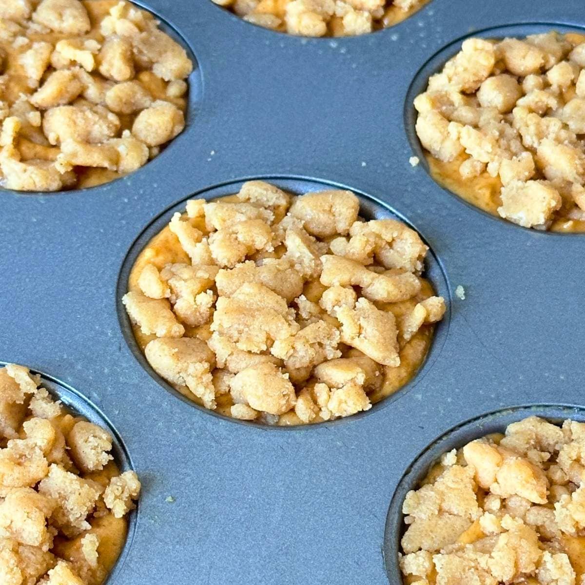 Unbaked pumpkin muffins topped with streusel.