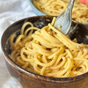 Bowl with creamy vegan cacio e pepe made with cashews with a fork.