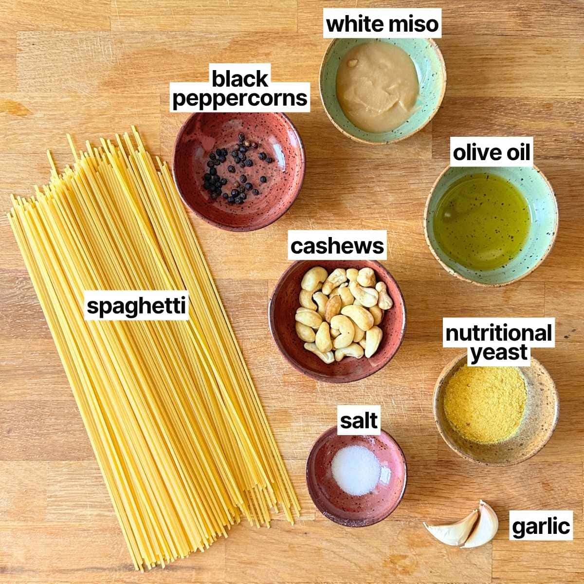 Ingredients needed to make vegan cacio e pepe: spaghetti, black peppercorns, white miso, cashews, olive oil, salt, nutritional yeast, and garlic.