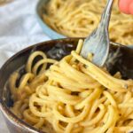 Bowl with creamy vegan cacio e pepe made with cashews with a fork.
